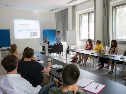 Teilnehmende eines Seminars an Tischen